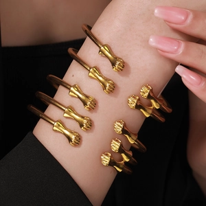 Close-up of five stacked gold-colored fist-shaped open bracelets on a person's wrist