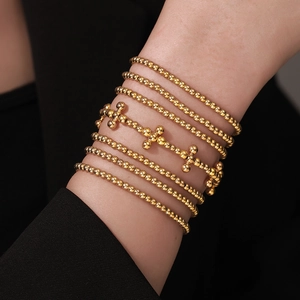 Close-up of golden multi-layer beaded bracelets with cross charm on female wrist