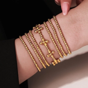 Bohemian style 7-piece layered gold bead bracelet set with cross charms on female wrist