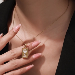 Detail of gold Tarot The Lovers necklace with zircon inlay on a female model