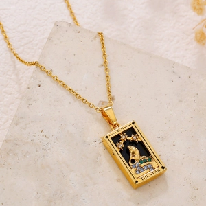 Macro detail of gold tarot pendant featuring The Star engraving and colored zircon stones