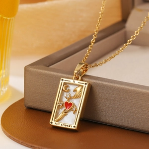 Macro detail of gold tarot lovers pendant with red heart and zirconia moon on a necklace