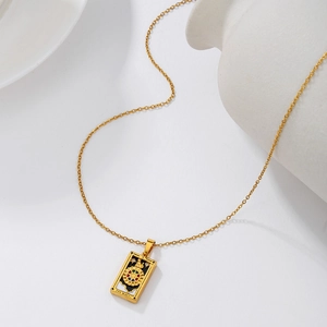 Detailed shot of gold tarot wheel pendant with black enamel inlay on white background