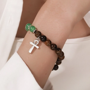 Detailopname van tijgeroog kralenarmband met zilveren Ankh-kruis gedragen om de pols