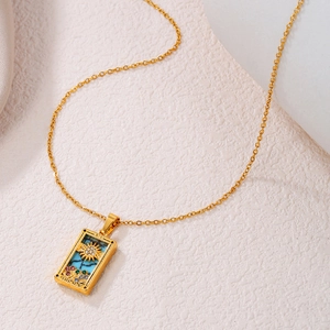Detail of a gold Tarot The Sun necklace with colorful zircons and blue enamel inlay