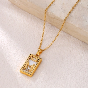 Macro shot of gold tarot The Lovers pendant with white shell inlay and zircon accents