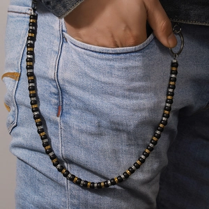 Détail d'une chaîne de pantalon avec perles noires mates et motif de méandre grec gravé