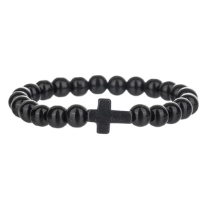 Detailopname van de matzwarte kralenarmband met een minimalistische kruisbedel