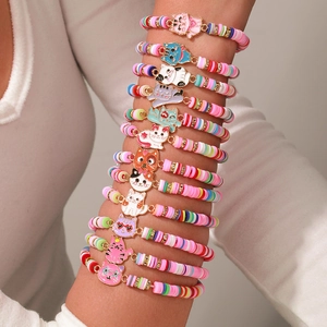 Detail von geschichteten Kinderarmbändern mit bunten Heishi-Perlen und Katzenanhängern