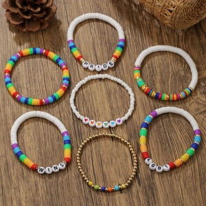 Close-up of rainbow bead bracelets set with heart charms and PRIDE letters on wood