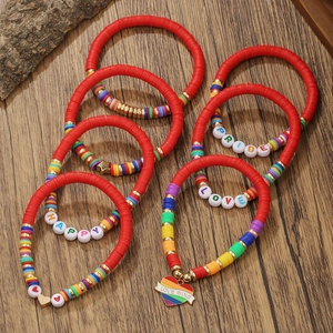 Detail of red polymer clay beads bracelet set with rainbow love heart charms on wood