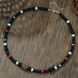Collier ethnique en perles de lave avec perle dorée vintage sur fond en bois sombre