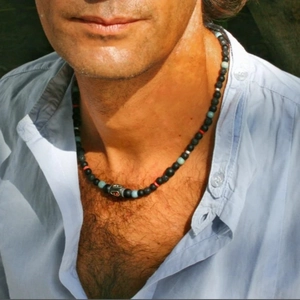 Collier de perles ethniques avec perles noires et touches bleues porté par un mannequin homme