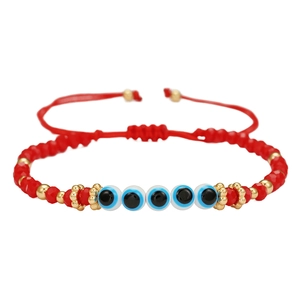 Detailweergave van rode boze oog armband met verstelbaar koord en gouden kralen