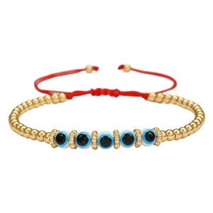 Macro-opname van rode gevlochten armband met blauwe boze oog kralen en gouden details