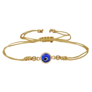 Detail van handgemaakte gouden touwarmband met blauwe evil eye hanger en verstelbare knoop