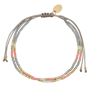 Detail van meerlaagse kralenarmband met verstelbaar grijs koord en gouden ronde hanger