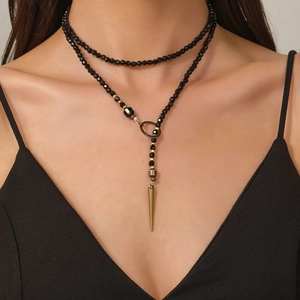 Macro detail van gothische zwarte kralen en bronzen spike hanger op een gelaagde ketting