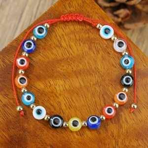 Detail van rode gevlochten armband met kleurrijke Evil Eye kralen en gouden tussenstukjes