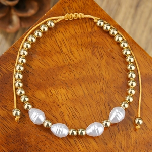 Macro-opname van gevlochten armband met gouden kralen en witte getextureerde kralen