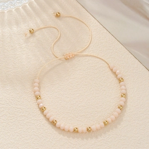 Detail van handgemaakte kralenarmband met roze matte kralen en gouden metalen kralen