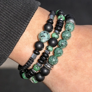 Close-up of stacked beaded bracelets featuring black agate and green natural stones