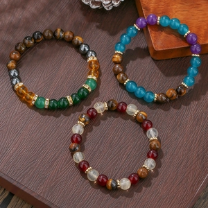 Detalle de pulseras de cuentas con ojo de tigre, ágata y cristal sobre madera