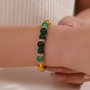 Detalle macro de pulsera de cuentas de cristal verde con espaciadores de strass dorado