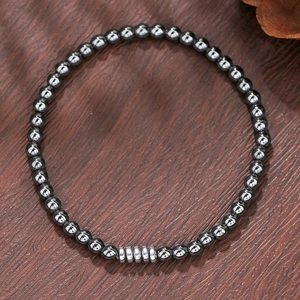 Detailopname van 6mm zwarte onyx en hematiet kralen op donkerhouten ondergrond