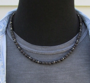 Close-up of men's beaded necklace with black lava stone and silver spacers on model