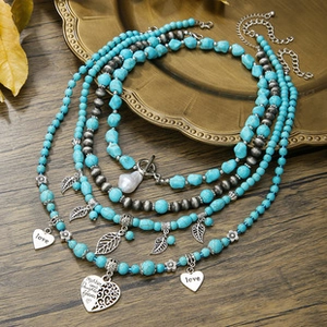 Detailed shot of turquoise beaded necklace with metal leaf and engraved heart charms