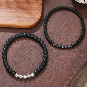 Detail van matzwarte agaat kralenarmbanden met zilveren accenten op een houten tafel