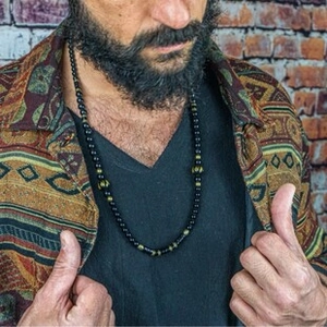 Detail of men's bohemian necklace with black beads and textured metallic spacers