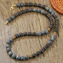 Detail van gelaagde kralenketting met zwarte agaat, metalen kralen en kreeftsluiting