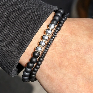 Detailopname van matte zwarte onyx kralen met gepolijste zilveren accenten op een pols