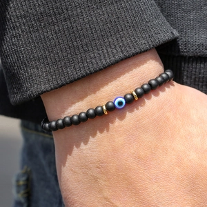 Detail van 6mm zwarte onyx kralenarmband met blauw boze oog bedeltje om de pols