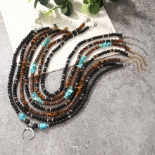 Detail van boho gelaagde kralenketting met turquoise, tijgeroog en een hoorn hanger