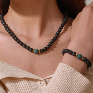 Close-up of layered black lava rock bead necklace and bracelet set with turquoise detail