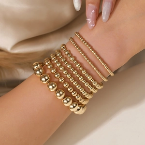 Set aus geschichteten Goldperlen-Armbändern in verschiedenen Größen am Modell