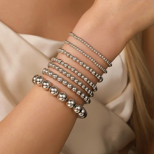 Nahaufnahme eines silbernen Perlenarmband-Sets in verschiedenen Größen auf Seidenstoff