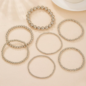 Makroansicht eines 7-teiligen Sets aus silbernen Perlenarmbändern in verschiedenen Größen