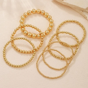 Detailansicht des mehrlagigen goldenen Perlenschmuck-Sets mit polierten Metallkugeln