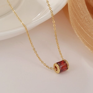 Dettaglio macro della collana placcata oro con pendente a cilindro e zirconi rossi taglio baguette