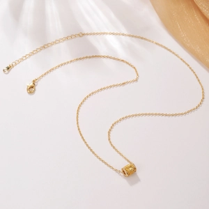 Dettaglio di una collana placcata in oro con pendente a cilindro in zircone giallo e chiusura