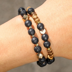 Close-up of double-layered men's lava stone bracelet with gold arrow charm and wood beads