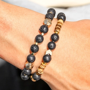 Detail of lava stone bracelet with golden metal spacers and wooden rings on wrist