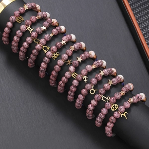 Twelve constellation natural stone beaded bracelets on black display stand with gold charms