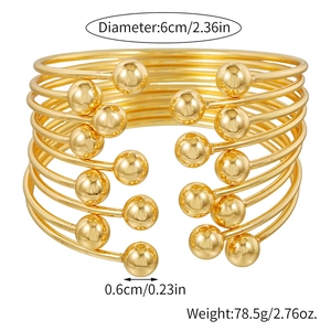 Detail view of 9-piece gold stacked open bangles with dimensions 6cm diameter and beads