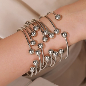 Macro shot of silver-plated layered open bangles with solid metal spheres on a model's arm