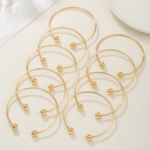 Detailed view of ten minimalist gold-plated open bangles with polished sphere ends